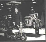 Geoff Duke with a Honda 4 in the background at the Earls Court show